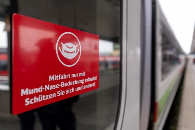 A sign with the inscription "Ride only allowed with mouth-nose covering! Protect yourself and others!" is stuck to the train door of a Deutsche Bahn train at Nuremberg main station.