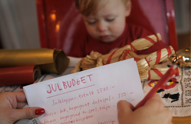 a woman drawing up a Christmas budget next to her son