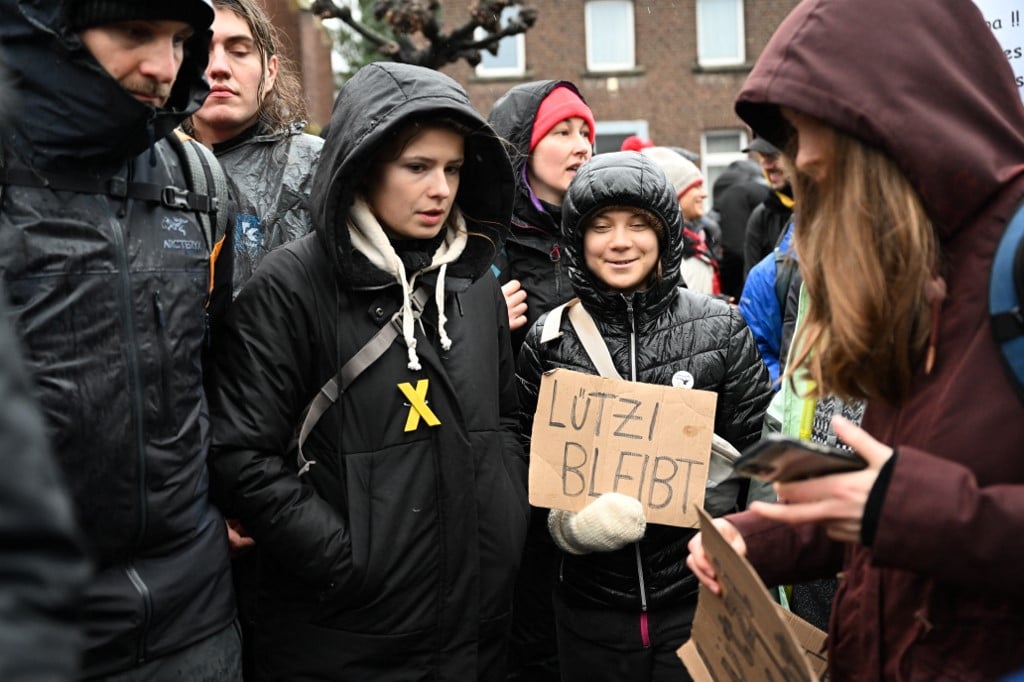 Swedish climate activist Greta Thunberg (C) holds a sign reading "Lützi stays" next to German climate activist Luisa Neubauer (2L) during a large-scale protest to stop the demolition of the village Lützerath