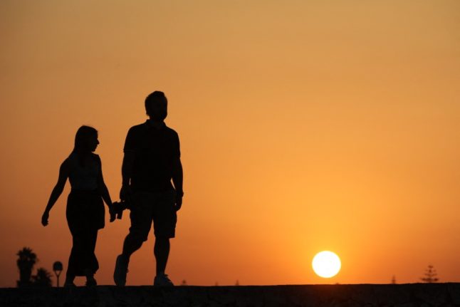 A couple enjoy sunset on the beach in Marzameni, southern Sicily.