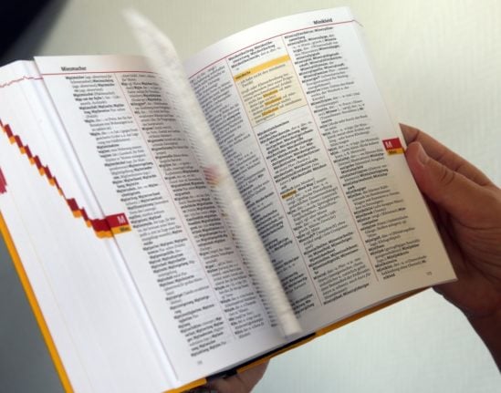 A woman consults the Duden German dictionary