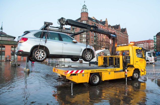 A truck tows away a car in a flooded street in Hamburg. 