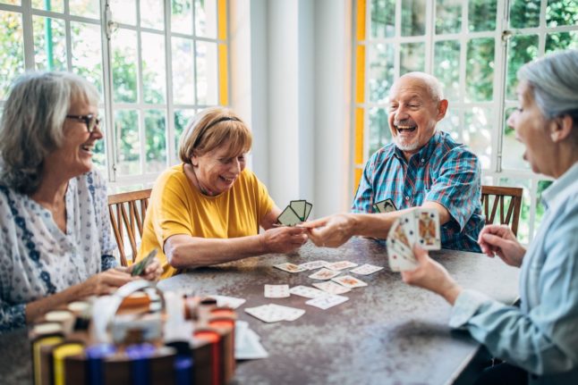 Elderly pensioners play cards in a care home.