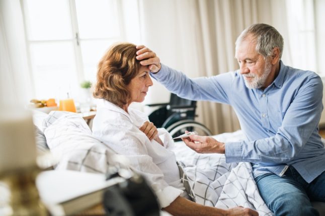 A carer measures a patient's temperature