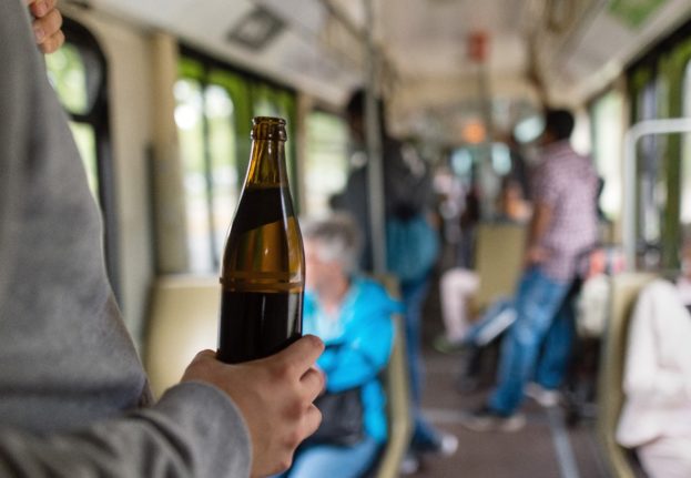 A person carries a beer on public transport in Hanover.