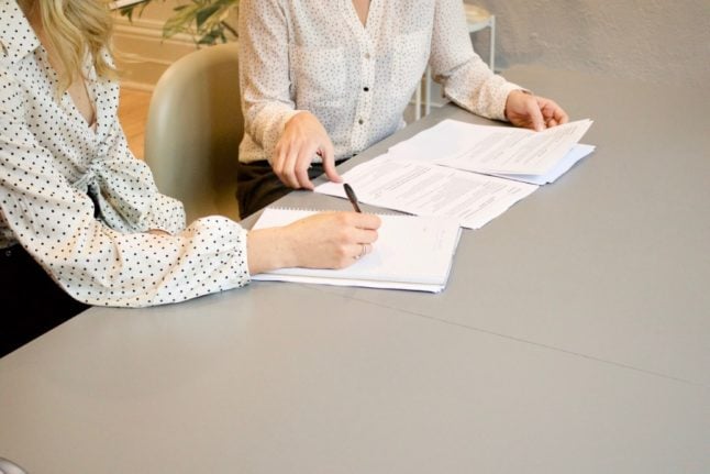 Two people signing documents in an office