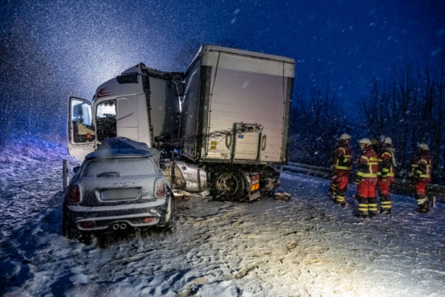 Emergency personnel stand on a slope where a semi-truck has slid into a car in Kierspe, North Rhine-Westphalia. 