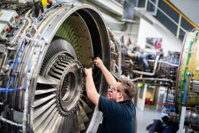 A man works on the engine of an aircraft in a Lufthansa Technik workshop.