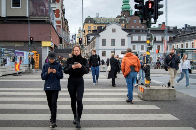 woman and boy walking through stockholm looking at their phones