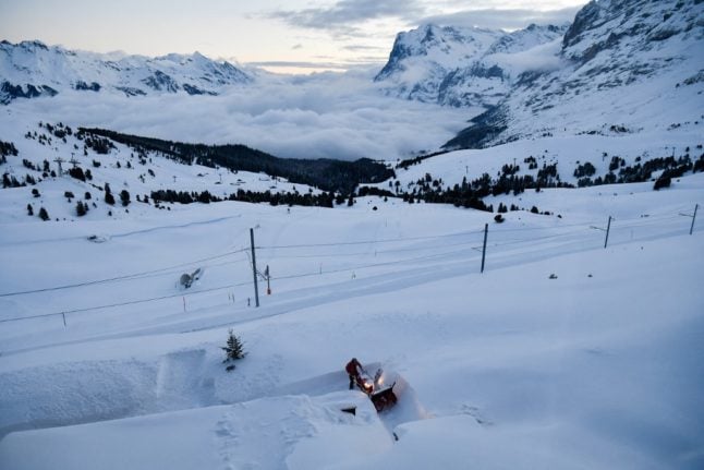 A man uses a machine to clear a path through the snow in the ski resort of Wengen in the Swiss Alps