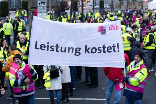 Members of the German dbb trade union hold up a banner reading 