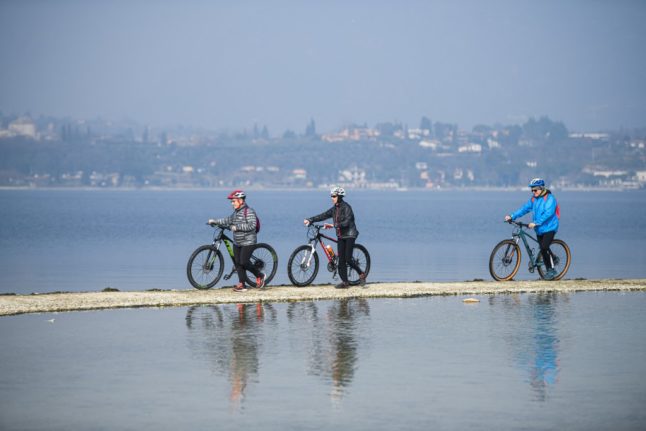 Tourists cycling to San Biagio island, Lake Garda
