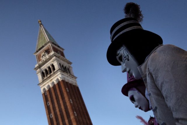 Masked revellers wearing a traditional carnival costume pose in St Mark Square, Venice