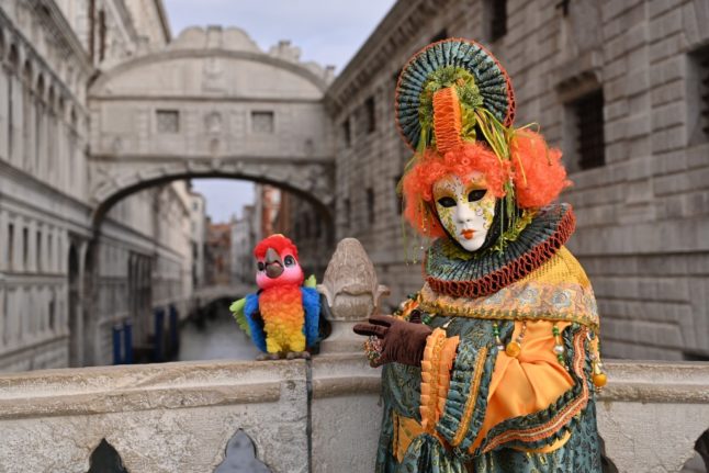 A masked reveller wearing a traditional carnival costume in Venice.