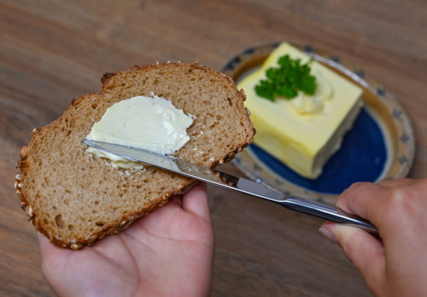 A girl spreads butter on a slice of bread.