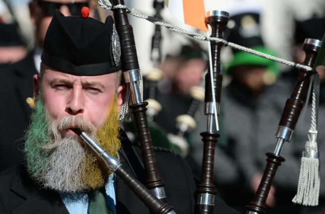 A participant of the St. Patrick's Day parade, who has dyed his beard in the Irish national colours, plays a bagpipe in Munich, Germany in 2017.