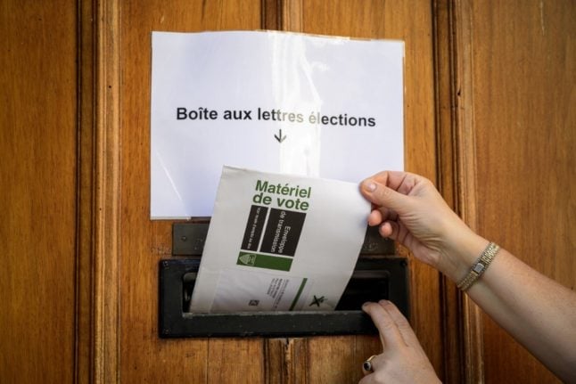 A woman inserts her postal voting envelope into the door of the polling station in Lausanne on September 29, 2019. - Voter concern about climate change could trigger a "green wave" in Switzerland's elections on October 20, 2019. 