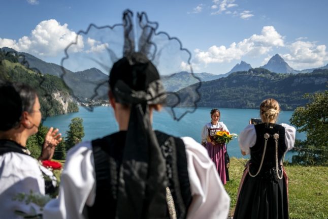 Women dressed in traditional Swiss costumes take a selfie at the Rütli meadow overlooking Lake Lucerne as part of Swiss National Day celebrations