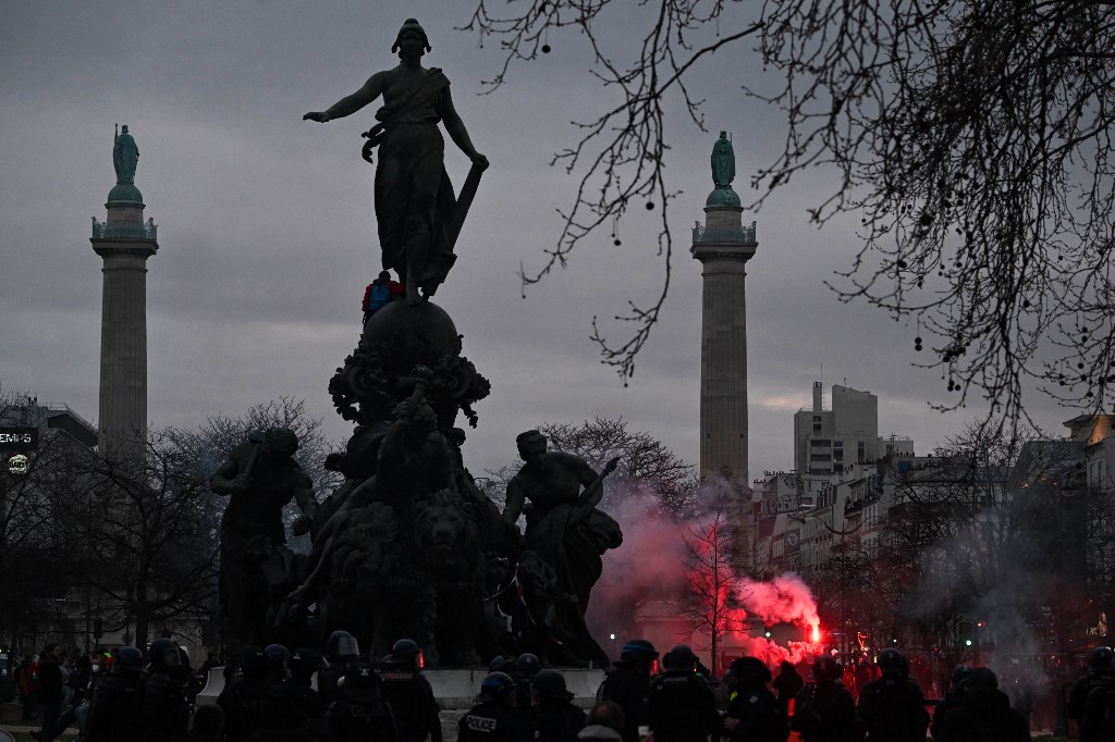 Protestors lights red flares during a demonstration on the pension reform in Paris