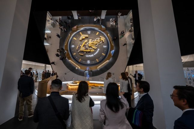 Participants stand at the booth of luxury Swiss watchmaker Ulysse Nardin, on the opening day of the luxury watch fair 'Watches and Wonders Geneva', in Geneva on March 27, 2023.