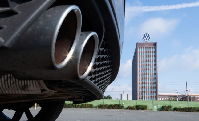 Exhaust pipes of a Volkswagen, photographed with the brand skyscraper at the VW plant in Wolfsburg.