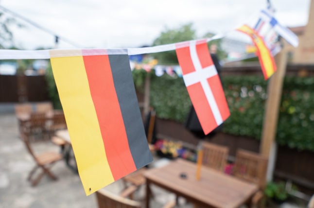 Flags of the countries participating in the European Women's Football Championship in 2022 hang in a pub garden.