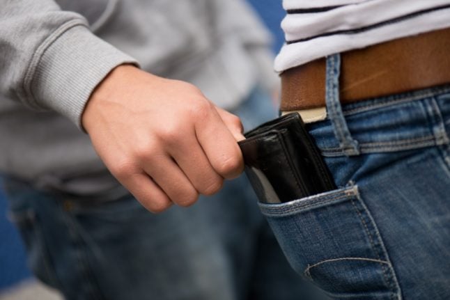 A pick pocket takes a wallet out of someone's back pocket