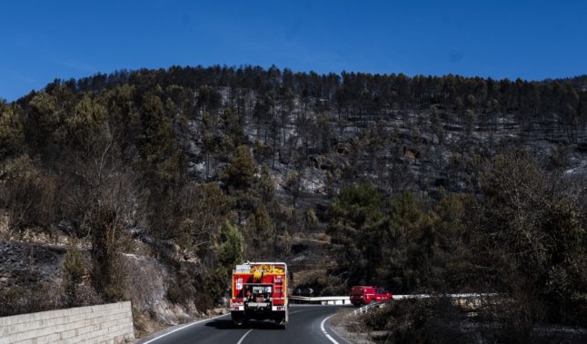 This picture shows firefighter vehicles driving past forest burnt by a wildfire near Castellon.