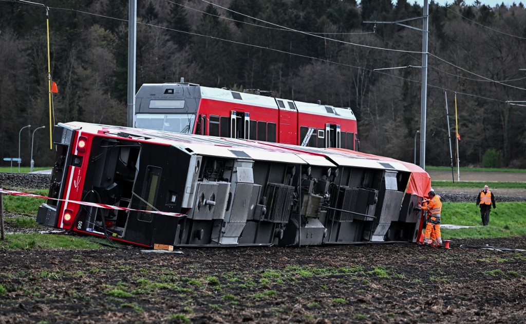 Train staff work on the site of a train derailment near lakeside town of Luscherz