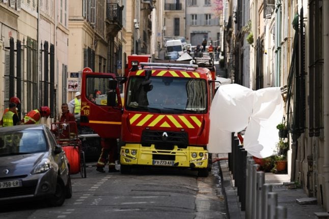 Firefighters install tarps as they prepare to remove a body from rubble at 'rue Tivoli' after a building collapsed in the street, in Marseille, southern France