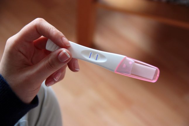 A woman gets a positive result on a pregnancy test.