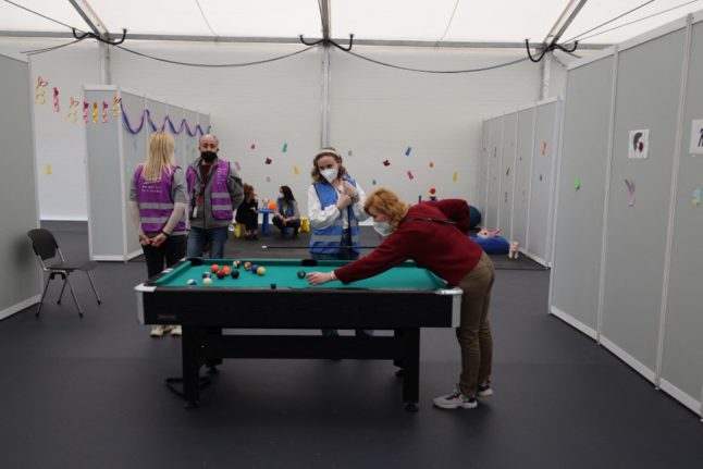 Workers and refugees are pictured near a pool table at the Ukraine Arrival Centre Tegel for Ukrainian refugees in Berlin