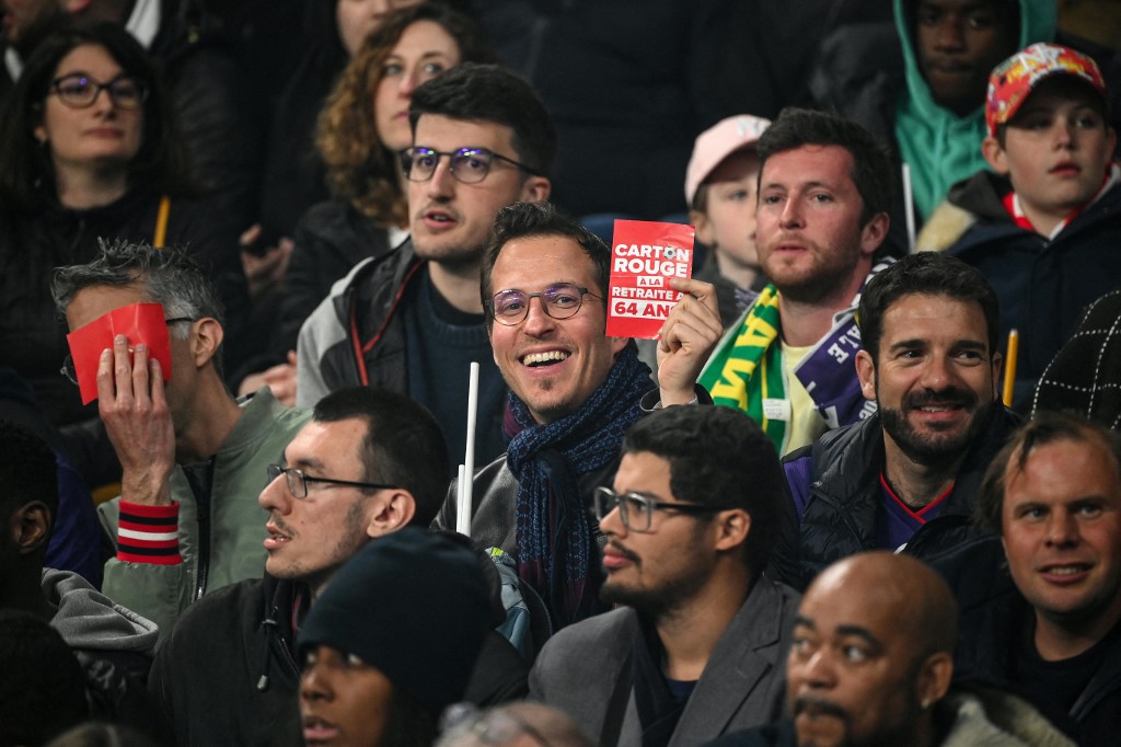 A spectator holds a placard reading " red card for the retirement at 64 "  during the French Cup final football match between Nantes (FC) and Toulouse (FC)