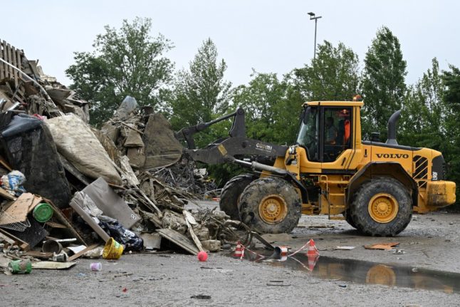 A digger adds to a pile of mud-covered furniture in Faenza