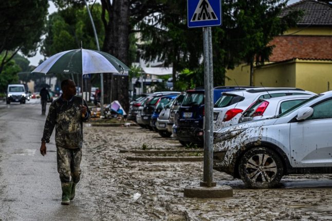 A resident walks down a muddy street in Faenza
