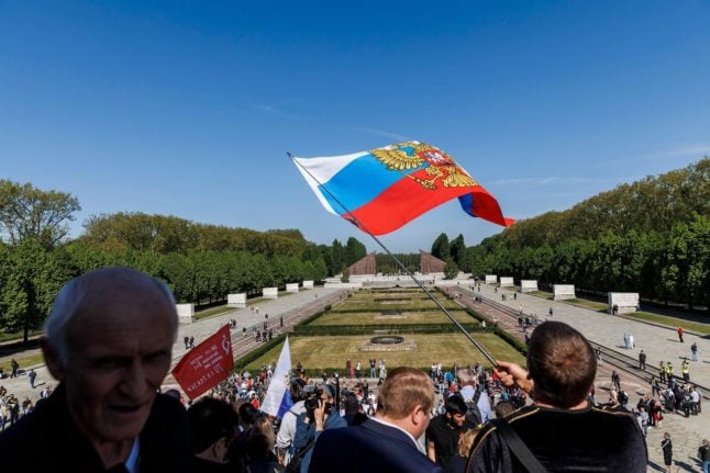 A man waves a Russian flag at a Berlin Soviet Memorial
