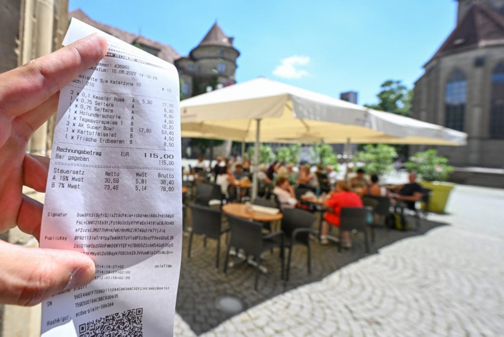 A waitress holds a bill for drinks and food in a restaurant in Stuttgart.