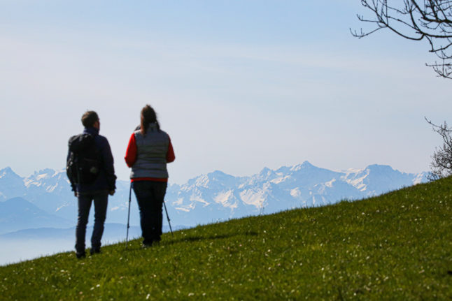 Hikers stand at the Höchsten vantage point in Baden-Württemberg and look out over the Alps.