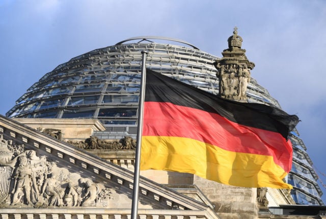The German flag flies in front of the dome of the Reichstag in Berlin.
