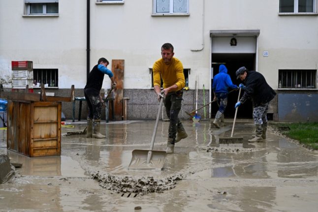 Volunteers clean mud from a flooded courtyard in Emilia Romagna
