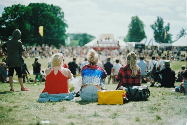 Pictured is a group of friends sat on the grass at a music festival.