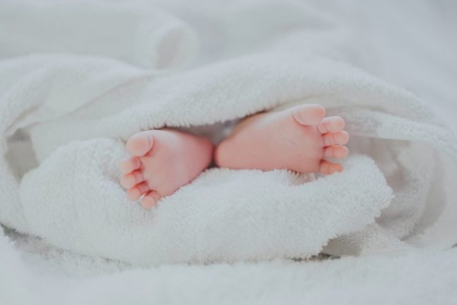 A baby lies on a blanket