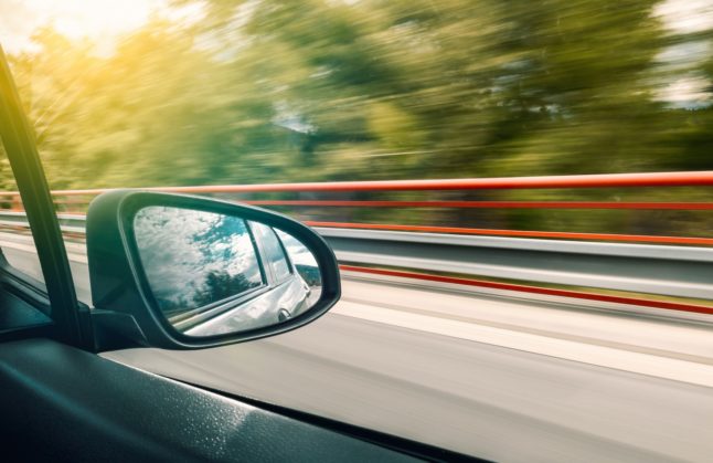 A car drives fast along a country road.