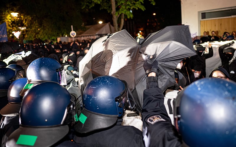 protesters and police at a take back the night demonstration in berlin. some protesters try to hide their faces with umbrellas