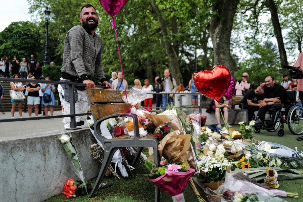 A man reacts next to flowers for the victims of a stabbing attack in Annecy