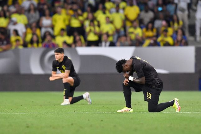 Brazil's forward Vinicius Junior takes the knee before the start of the international friendly football match between Brazil and Guinea at the RCDE Stadium near Barcelona