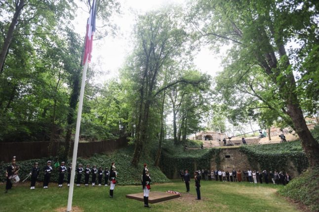 French President Emmanuel Macron (2-R) offers flowers at the site where the French resistance fighters were executed during a ceremony marking the 83rd anniversary of late French General Charles de Gaulle's World War II resistance call.