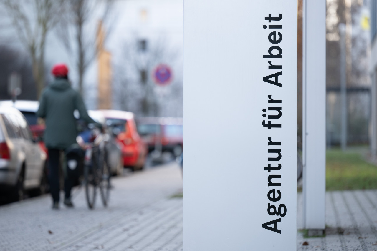 A woman walks past the sign for the Employment Agency