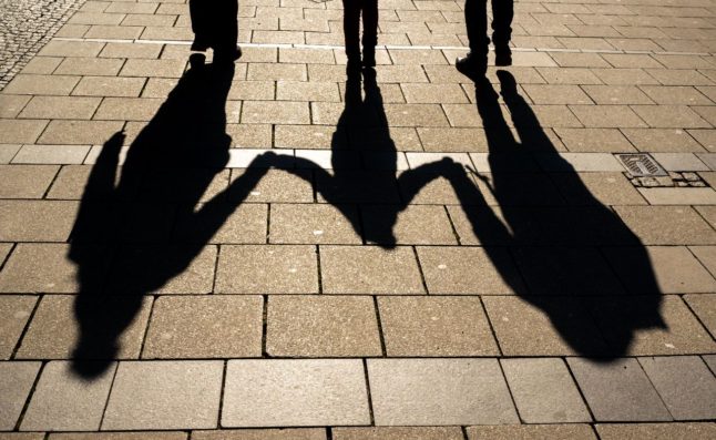 Parents hold hands with their child in Germany.