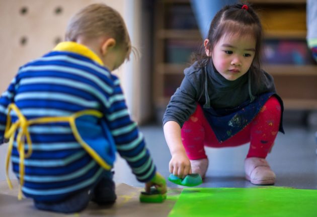 Children play a colouring game at a German 'Sprach Kita'.